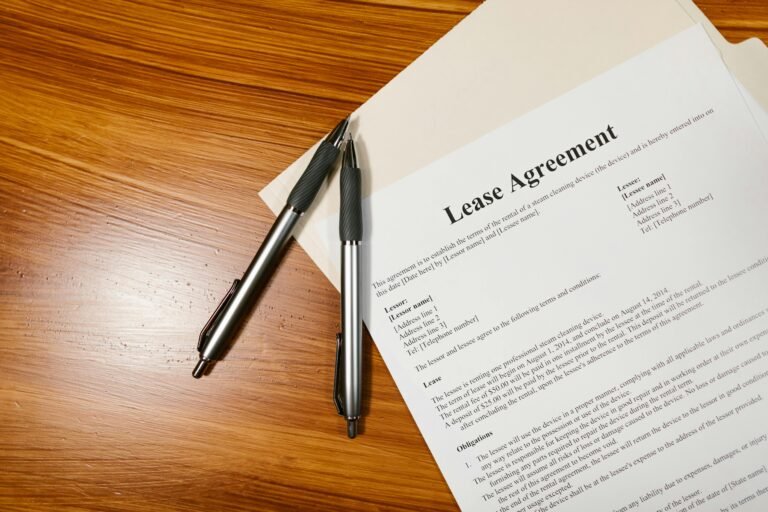 High-angle view of a lease agreement and pens on a wooden desk.